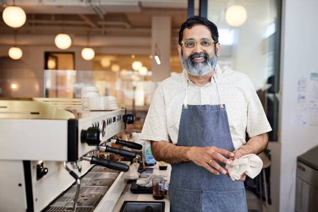 Smiling mature owner with eyeglasses standing by espresso machine Los Angeles, California, United States CR_JAJEES221212-1083365-01 ,model released, Symbolfoto ,property released