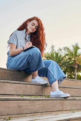 Creative Highlights Symbolbilder Young redhead woman writes in a notebook outdoors Alicante, Valencian Community, Spain CR_CRBL210706-782405-01 ,model released, Symbolfoto