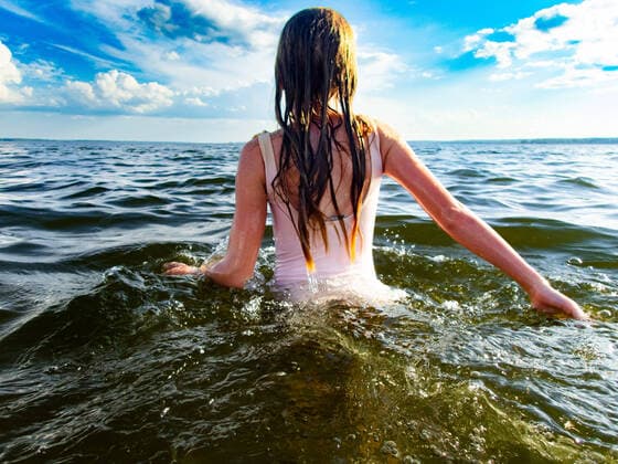 Creative Highlights Symbolbilder Young girl walks in ocean with blue sky and sunshine in swimsuit Munising, Michigan, United States CR_WVNP221220-1088028-01 ,model released, Symbolfoto