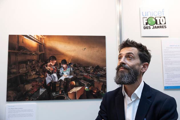 Der Fotograf Eduardo Soteras am 22.12.2022 vor dem Unicef-Foto des Jahres 2022 in der Ausstellung im Haus der Bundespressekonferenz in Berlin. Das Unicef-Foto des Jahres 2022 des renommierten argentinischen Fotografen Eduardo Soteras zeigt zwei Kinder, die sich in der zerstoerten Bibliothek einer Grundschule in der aethiopischen Region Tigray in Buecher vertiefen. (Siehe epd-Meldung vom 22.12.2022) EDITORIAL USE ONLY