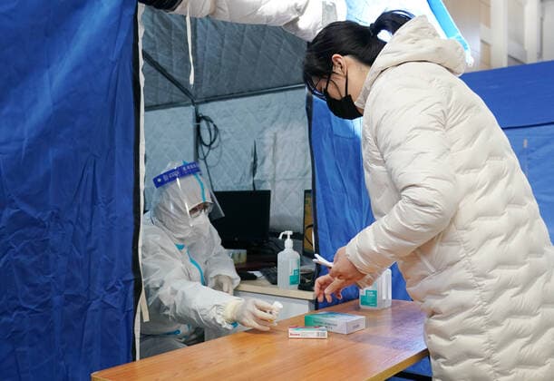 Coronavirus in China, provisorische Notunterkunft für Patienten mit Fieber in Peking (221224) -- BEIJING, Dec. 24, 2022 -- A medical worker passes medicine to a citizen in a makeshift fever clinic in Guang an Gymnasium in Beijing, capital of China, Dec. 24, 2022. In order to facilitate fever patients to seek medical treatment and ensure residents medical needs, some hospitals in Beijing set up makeshift fever clinics in gymnasiums to provide services such as diagnosis, prescription issuing and medicine dispensing for citizens. ) CHINA-BEIJING-GYMNASIUM-FEVER CLINIC (CN) ZhangxChenlin 