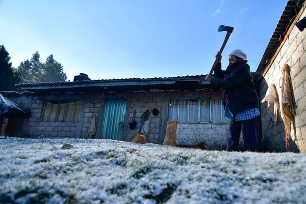 December 26, 2022, Zinacantepec, Mexico : Snow blankets the ground as a woman chops firewood outside her home in Zinacantepec. Due to recent low temperatures the community of La Joya , located in the lower part of the volcano Xinantecatl , received its first snowfall of the year. Zinacantepec Mexico - ZUMAe321 20221226_zia_e321_066 Copyright: xArturoxHernandezx