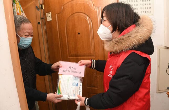 News Themen der Woche KW52 (221227) -- BEIJING, Dec. 27, 2022 -- A community worker (R) hands a care package to a resident in a community in Yangfangdian Subdistrict of Haidian District in Beijing, capital of China, Dec. 27, 2022. In Yangfangdian Subdistrict, care packages including medicines and COVID-19 prevention materials have been offered for senior residents living alone and those with disabilities. Shared medical kits have also been provided for residents in case of emergency. ) CHINA-BEIJING-COVID-19 PREVENTION-CARE PACKAGES (CN) RenxChao 