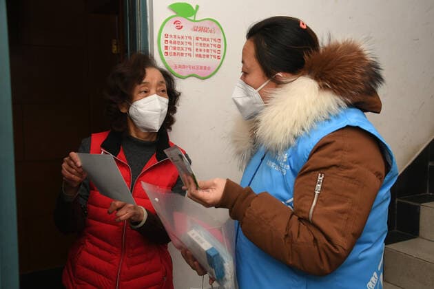 (221227) -- BEIJING, Dec. 27, 2022 -- A community worker (R) talks with a resident in a community in Yangfangdian Subdistrict of Haidian District in Beijing, capital of China, Dec. 27, 2022. In Yangfangdian Subdistrict, care packages including medicines and COVID-19 prevention materials have been offered for senior residents living alone and those with disabilities. Shared medical kits have also been provided for residents in case of emergency. ) CHINA-BEIJING-COVID-19 PREVENTION-CARE PACKAGES (CN) RenxChao 