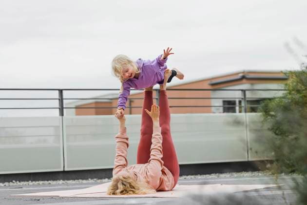 IMAGO Creative, Urban Lifestyle Mother balancing girl on legs lying down at rooftop model released, Symbolfoto, München Bayern Deutschland Gertrud-Grunow-Strasse AANF00412