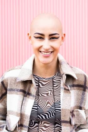 Creative Highlights Symbolbilder Cheerful young woman with shaved head in front of pink wall model released, Symbolfoto property released, DAMF01172