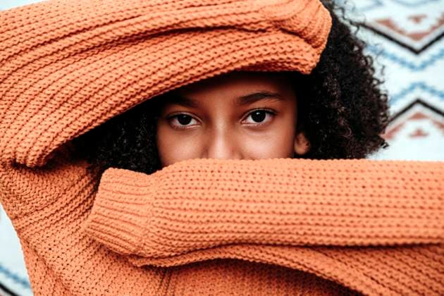 Creative Highlights Symbolbilder Girl wearing orange sweater covering face model released, Symbolfoto property released, EBBF07195