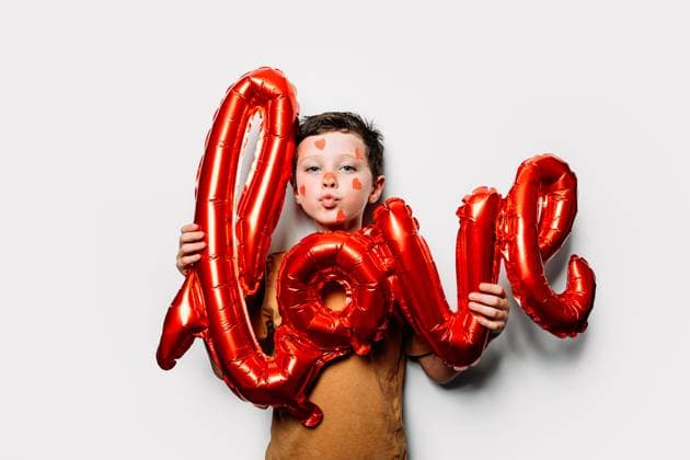 Creative Highlights Symbolbilder Cute boy with hearts on face and Love shaped balloon pouting lips and looking at camera against gray wall on Saint Valentine Day, Model released HodeiUnzueta_ID11304_339922_039 Copyright: xHodeixUnzuetax MR