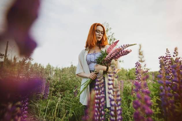 Teenage girl standing with lupin flowers under sky model released, Symbolfoto, IEF00256