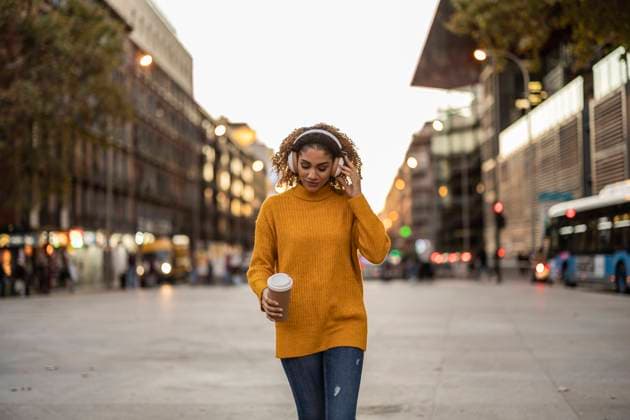IMAGO Creative, Lifestyle, Tik Tok-Trend thatgirl Woman listening to music through wireless headphones holding disposable cup walking on footpath model released, Symbolfoto, JCCMF08587