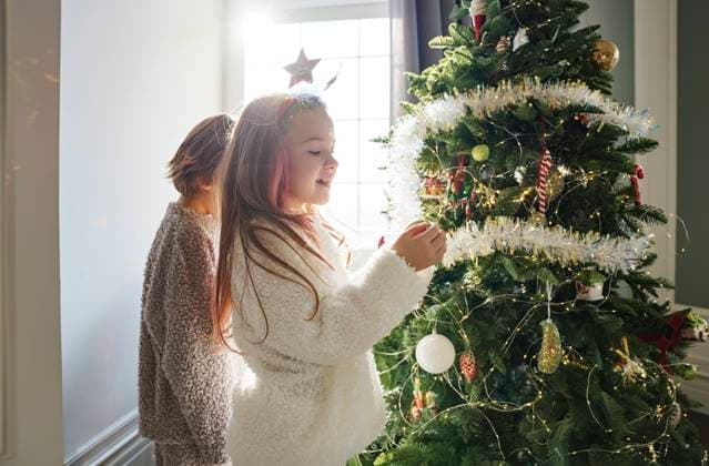Happy girl with brother decorating Christmas tree in bedroom at home model released, Symbolfoto property released, MDOF00390