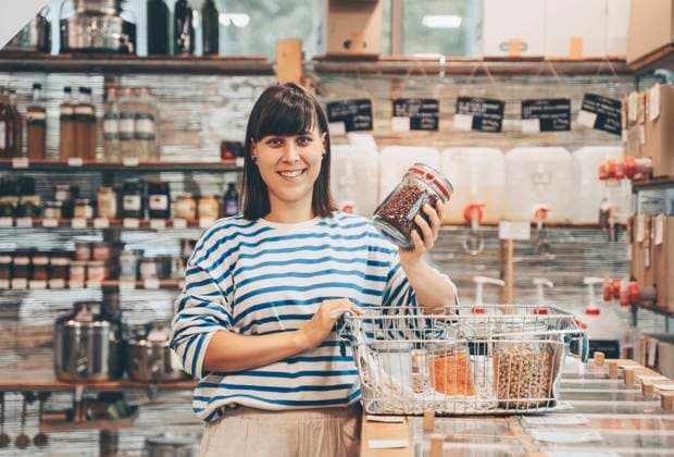 Smiling woman holding mason jar at counter in zero waste store model released, Symbolfoto property released, NDEF00157