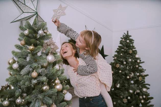 Daughter putting star on Christmas tree with mother at home model released, Symbolfoto property released, NDEF00256