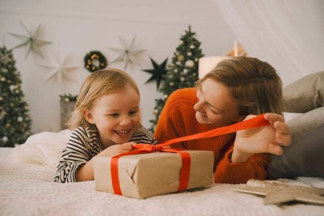 Mother unwrapping gift with daughter on bed at home model released, Symbolfoto property released, NDEF00261