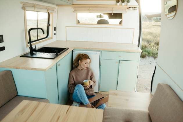 Young digital nomad sitting with coffee cup looking at laptop inside motor home model released, Symbolfoto property released, RCPF01504