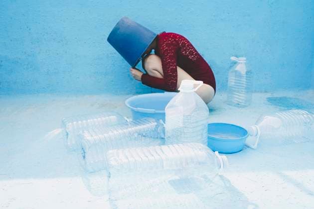 Creative Highlights Symbolbilder Woman with head inside bucket by plastic bottles in empty swimming pool model released, Symbolfoto, SVCF00229