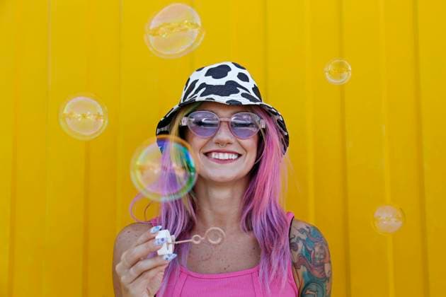 Happy woman holding bubble wand in front of yellow wall model released, Symbolfoto property released, SYEF00145