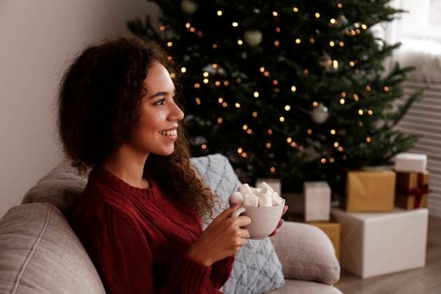 Happy young woman holding cup of marshmallow cocoa sitting on sofa at home model released, Symbolfoto property released, SYEF00172
