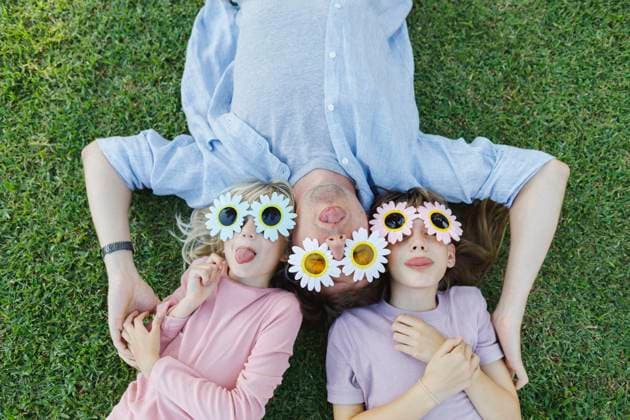 Playful father and daughters with flower sunglasses relaxing and having fun in grass model released, Symbolfoto, TYF00484
