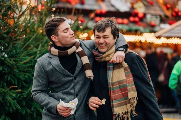 Smiling man eating trdelnik with arm around father enjoying at Christmas market model released, Symbolfoto, VSNF00200