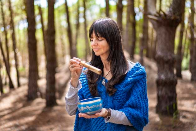 Woman playing a Tibetan singing bowl in the woods. Pinamar, Buenos Aires Province, Argentina R_SHVL230110-1092380-01 ,model released, Symbolfoto