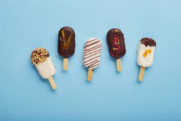 Mousse dessert with fruit flavors in the form of popsicle ice cream on blue background. Mousse dessert with fruit flavors in the form of popsicle ice cream covered with white and dark chocolate on a blue background. Copyright: xZoonar.com BurakovaxIrinax 18286104