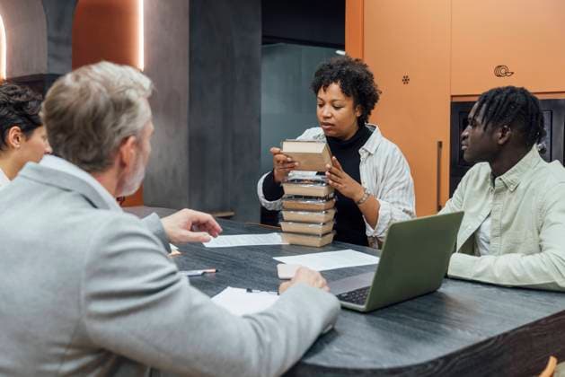 Young businesswoman holding lunch boxes with colleagues sitting at table model released, Symbolfoto property released, VPIF07751