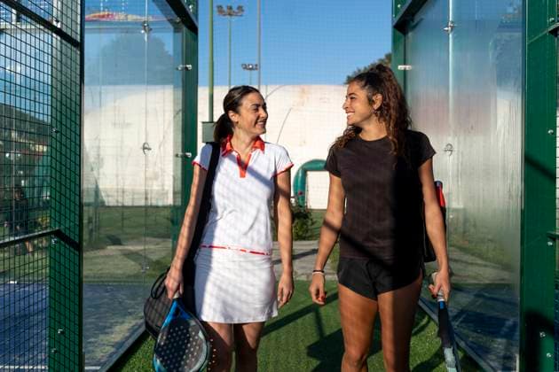 Happy female friends together standing at sports court on sunny day model released, Symbolfoto property released, FMOF01591