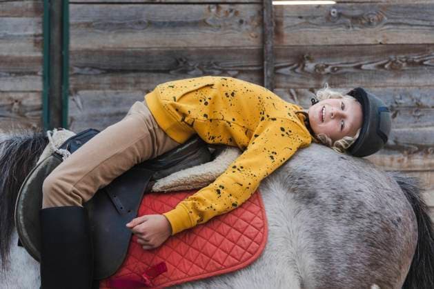 IMAGO Creative, Kinder auf dem Reiterhof Happy boy lying on Dapple gray horse at ranch model released, Symbolfoto property released, NJAF00092