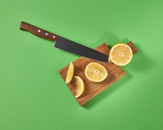 Half and slices of fresh tropical yellow lemon on a wooden cutting brown board with a steel knife. View from above. Top view of halfs and slices of natural lemon on a cutting wooden board. A sharp steel knife is cut by organic citrus fruit. Copyright: xZoonar.com IaroslavxDanylchenkoxphoographerxxartjazz.com.uax 12388467