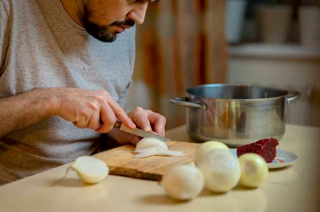 Man chopping white onion on cutting board in kitchen model released, Symbolfoto property released, ANAF00888