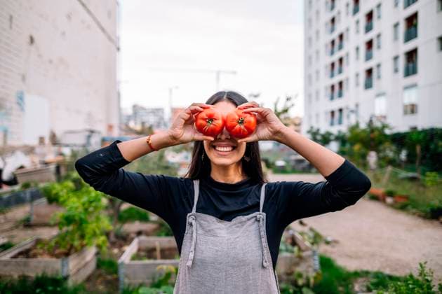 Happy woman holding tomatoes over eyes in urban garden model released, Symbolfoto, GDBF00034