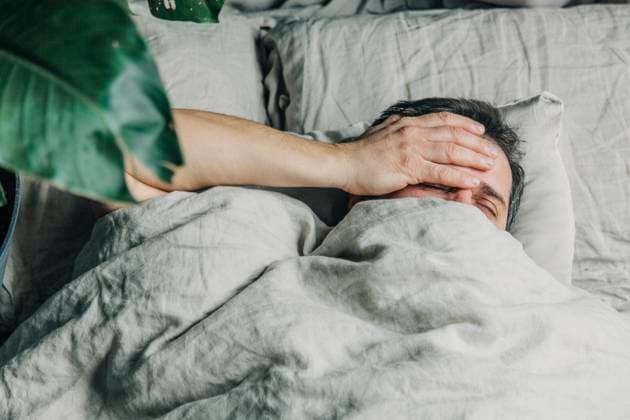Man with hand on head lying in bed model released, Symbolfoto, VSNF00376