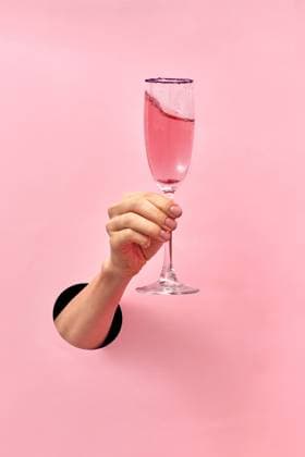 Rose wine glass in a female s hand from the hole in the wall. Woman hand from the hole holds glass with rose wine on a pastel pink background, copy space. Holiday concept. Copyright: xZoonar.com IaroslavxDanylchenkoxphoographerxxartjazz.com.uax 14756520