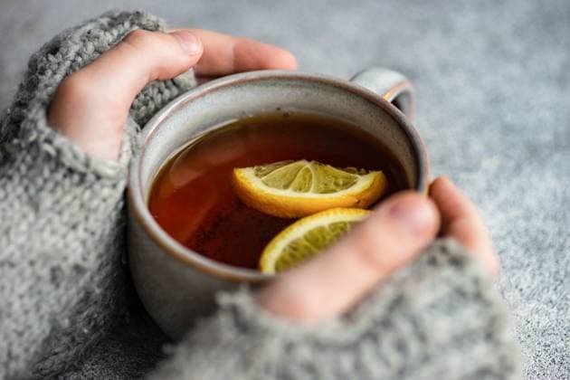 Kid hands in mittens hold cup of tea with lemon on grey concrete background AnnaBogush_ID12525_380266_001 Copyright: xAnnaxBogushx Model Released