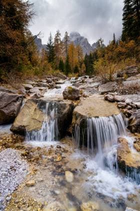 Creative Highlights World Picturesque scenery of rapid waterfall flowing through forest with coniferous trees on cloudy day in Dolomites Mountain range AlbertPalen_ID12533_380407_019 Copyright: xAlbertxPalenx Model Released