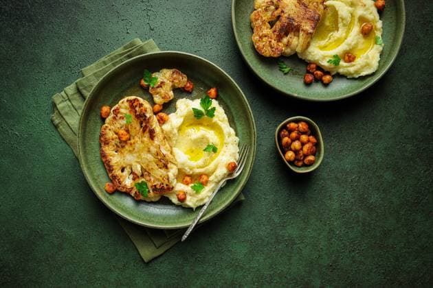 Top view of delicious roasted cauliflower with mashed potatoes and spiced harissa chickpeas served on ceramic plate on green table background CintiaViudez_ID12615_383233_006 Copyright: xCintiaxViudezx Model Released