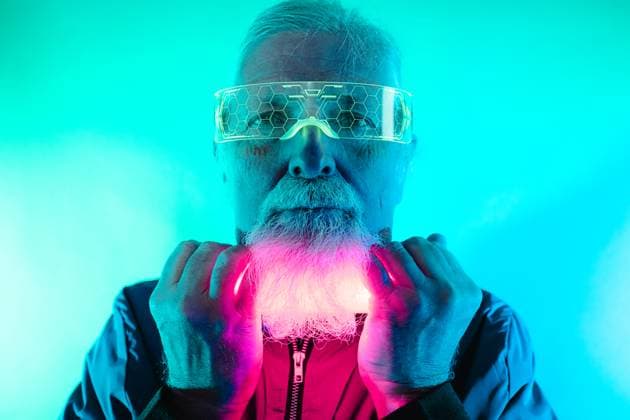 Positive bearded elderly male hipster in glasses looking at camera with neon light under face in studio, Model released HodeiUnzueta_ID12692_385588_020 Copyright: xHodeixUnzuetax MR