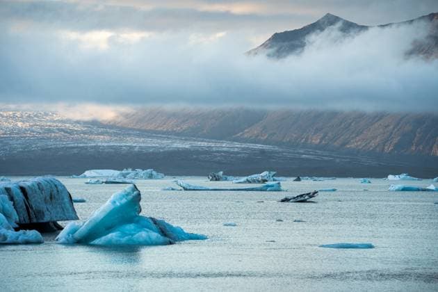 Creative Highlights World Picturesque scenery of rippling sea water with iceberg near high rocky mountain ridge covered with thick clouds in Iceland PabloMenendez_ID11384_342016_056 Copyright: xPabloxMenendezx Model Released
