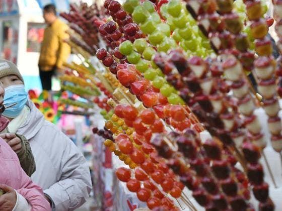 (230205) -- RENQIU, Feb. 5, 2023 -- Tourists taste Tanghulu, a traditional Chinese snack of candied fruit, in Houlihua Village of Renqiu, north China s Hebei Province, Feb. 5, 2023. People celebrate the Lantern Festival, the 15th day of the first month of the Chinese lunar calendar, with various traditional customs across the country. ) CHINA-LANTERN FESTIVAL-TRADITIONAL CUSTOM (CN) MuxYu 