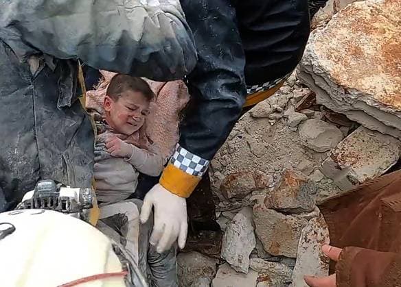 Rescue men evacuate a child pulled out of the rubble following an earthquake in northwestern Syrian Idlib in the rebel-held part of Idlib province, on February 6, 2023. - Hundreds have been reportedly killed in Turkey and Syria after a 7.8-magnitude earthquake that originated in Turkey and was felt across Middle East countries.  SYR2023020630r SyriaxCivilxDefense