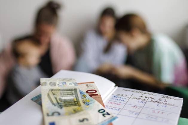 Haushaltsbuch mit fuenfunddreissig Euro. Im Hintergrund eine Mutter mit drei Kindern. Bonn Deutschland *** Household book with fuenfunddreissig euro In the background a mother with three children Bonn Germany Copyright: xUtexGrabowsky photothek.dex