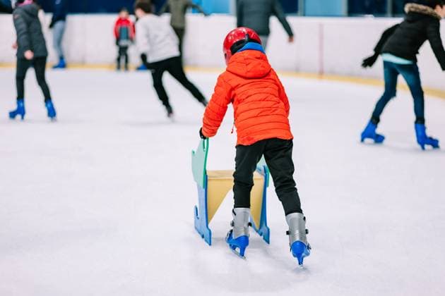 IMAGO Creative, Jahreszeit Winter, Eislaufen Back view boy in warm clothes and protective helmet learning ice skating with helper on ice rink, Model released HodeiUnzueta_ID12779_387543_019 Copyright: xHodeixUnzuetax MR