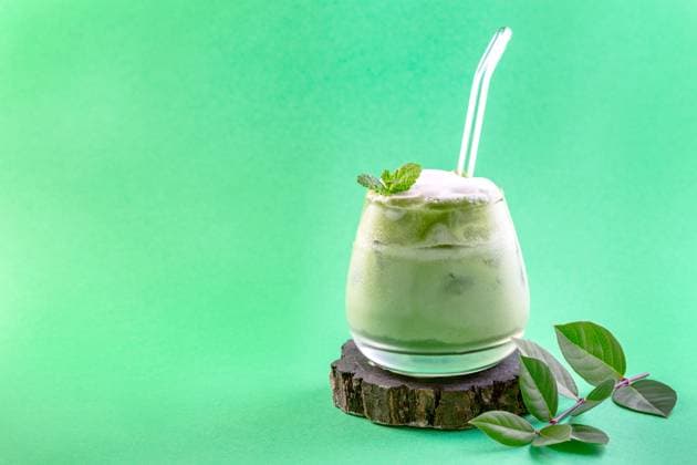Ice green matcha latte. Glass of cold green matcha tea mixed with ice cubes and milk on a wooden stand. Copy space. Concept of iced summer drinks. Copyright: xZoonar.com MarinaxSaprunovax 18784317