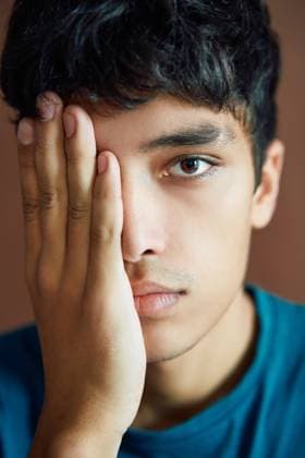 Close up portrait of young man covering half face with a hand and looking by one eye Close up portrait of young man covering half face with a hand and looking by one eye on studio background. Man beauty concept Copyright: xZoonar.com ViktorxGladkovx 16470011 ,model released, Symbolfoto ,property released