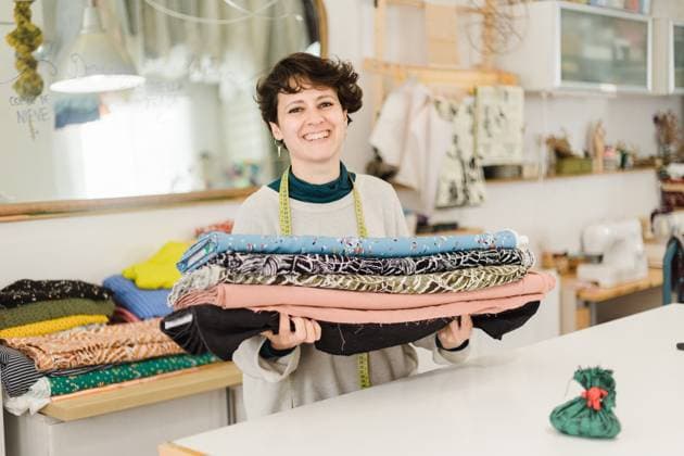 Cheerful female designer in casual clothes with measuring tape around neck looking at camera and smiling while standing with colorful textile in atelier, Model released, Property released AlbaCaro_ID12631_384029_058 Copyright: xAlbaxCarox MR