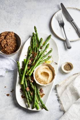 Top view of yummy hummus with asparagus served on white plate near bowl of crispy seed crackers on marble table in kitchen GeorgiaGold_ID12873_391218_001 Copyright: xGeorgiaxGoldx Model Released