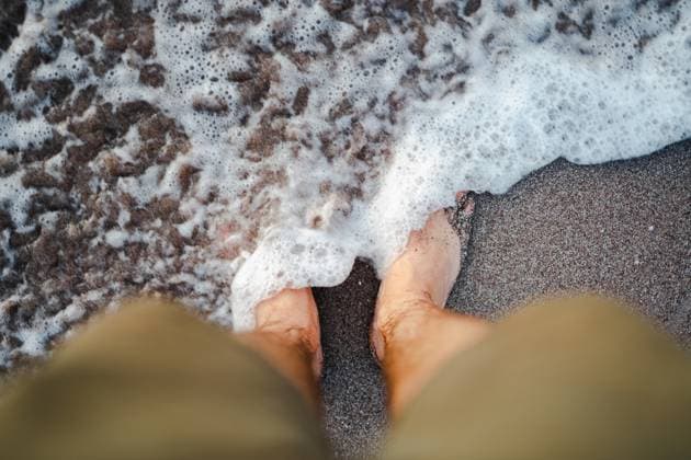 Creative Highlights Symbolbilder Top view of unrecognizable barefoot male traveler in shorts standing on sandy beach in waving sea water during summer vacation in Costa Rica resort, Model released PabloMenendez_ID11380_341768_056 Copyright: xPabloxMenendezx MR