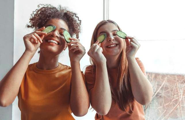 Close up photo of two best girlfriends spending time together having fun while applying cucumber slices on eyes holding them with hands Close up photo of two best girlfriends spending time together having fun while applying cucumber slices on eyes holding them with hands, looking up in camera broadly smiling. Friendship concept Copyright: xZoonar.com DashaxPetrenkox 18299047 ,model released, Symbolfoto ,property released