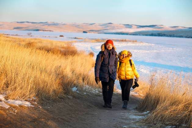 Romantic couple of tourists dressed in warm winter sportswear with tourist backpacks walking in the snow Romantic couple of tourists dressed in warm winter sportswear with tourist backpacks walking in the snowy mountains in an incredible sunset. Ogoi island, Baikal lake. Family, rest. Copyright: xZoonar.com DashaxPetrenkox 19148163 ,model released, Symbolfoto ,property released